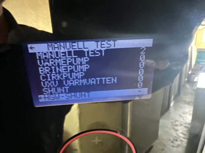 Digital display visar meny för teknisk utrustning, reflektioner, suddig bakgrund, text på svenska.