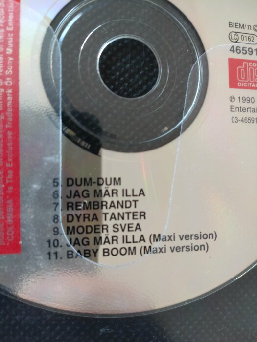 CD-skiva, låtlista, musikalbum, år 1990, transparent fodral, text i svart och rött.