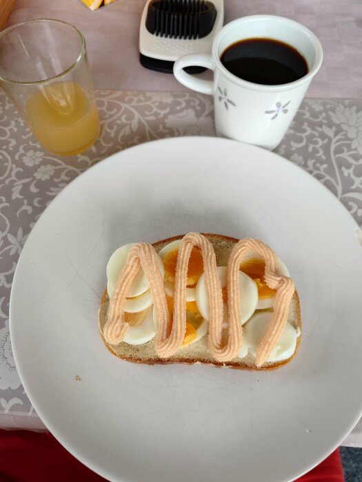 Frukostbricka med smörgås, kokt ägg, kaviar, kaffe, apelsinjuice, och hårborste i bakgrunden.