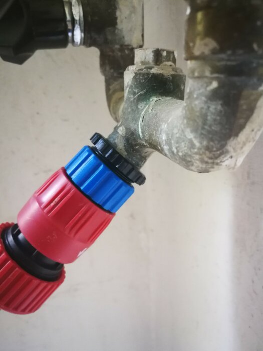 Vattenkran med kopplad snabbkoppling, väggmonterad, patina, använd inom trädgårdsskötsel eller bevattning.