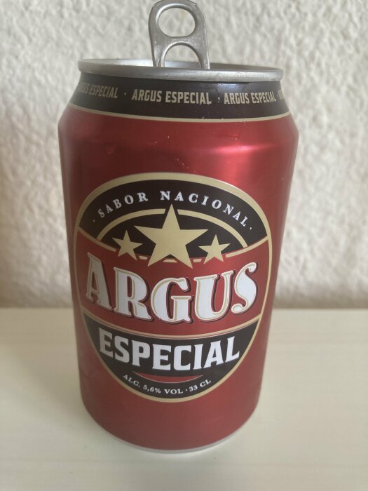 Röd ölburk, "Argus Especial", stjärna, 5,6% alkoholvolym, pull-tab öppen, vita text, bakgrund.