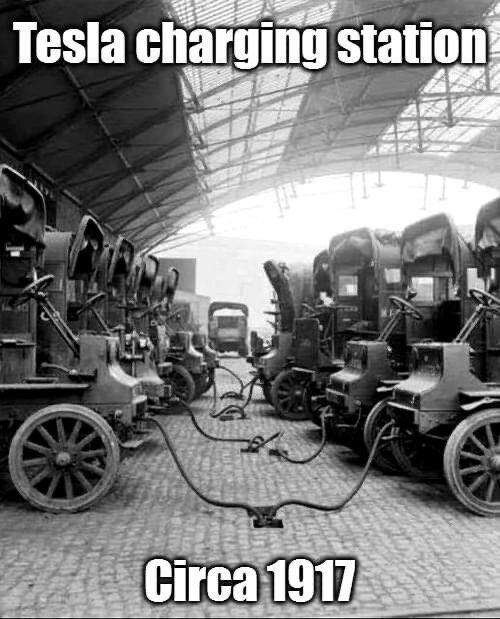 Svartvit bild av gamla fordon, ironiskt titulerad "Tesla laddningsstation", faktiskt inte elektriska bilar. Cirka 1917.