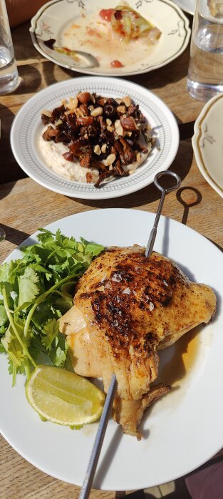 Grillad kyckling med koriander, lime, en bakad rätt och vatten i solljus på uteservering.