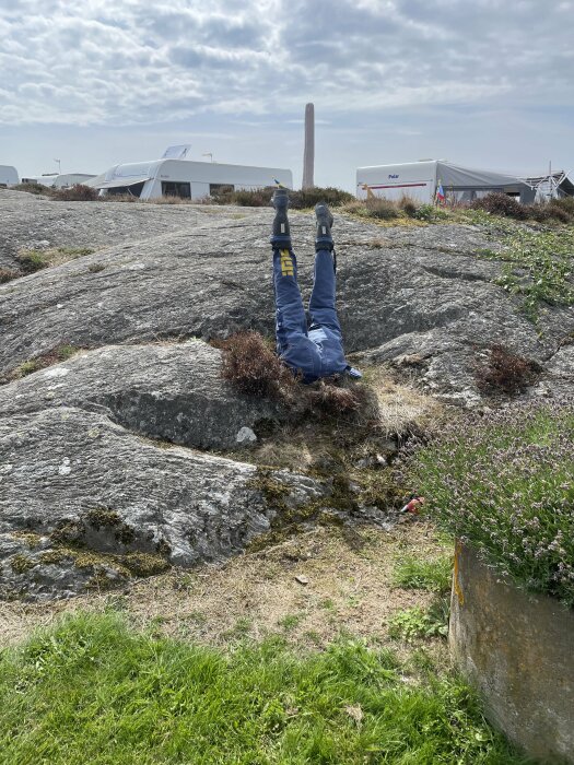 Person benen i luften; klippa; tält; molnig himmel; humoristiskt; upp-och-ner.