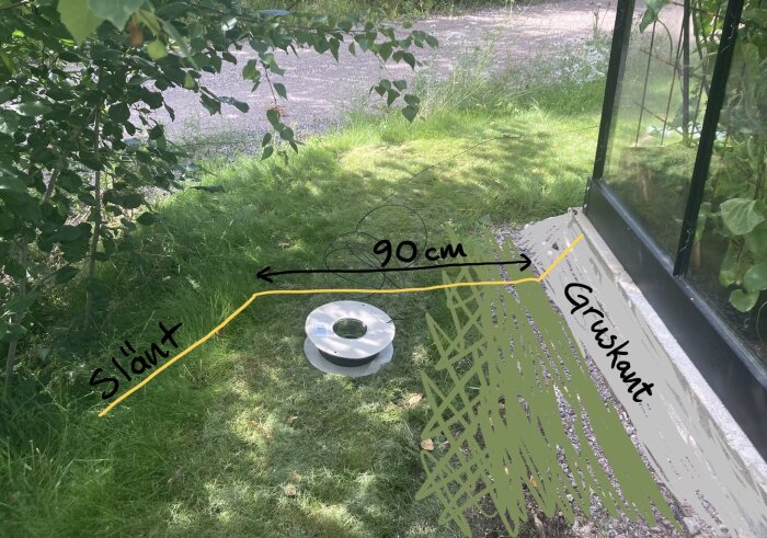 Utomhusvy med ventilationstrumma, lutande mark, 90 cm mått, gräskant och buskar.