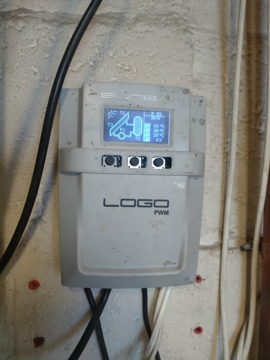 En enhet monterad på vägg med skärmdisplay, kablar, märkt "LOGO PWM". Ser ut som styrenhet.