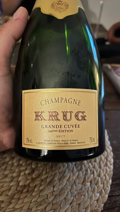 Närbild på en flaska Krug Grande Cuvée champagne, brut, 166:e upplagan, hålls, del av hand syns.