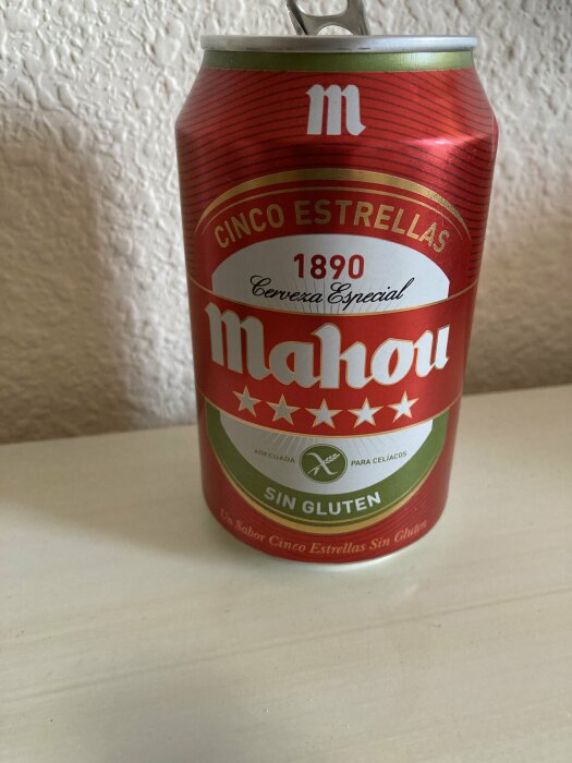 Röd burk av Mahou Cinco Estrellas glutenfri öl mot ljus bakgrund.