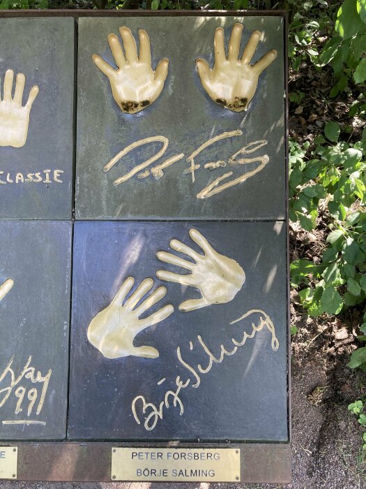 Handavtryck och signaturer ingraverade i plattor, troligen kända personers, monterade utomhus.