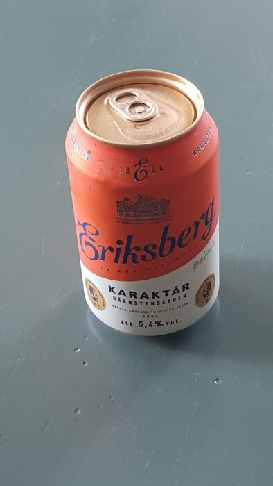 En Eriksberg ölburk på en grå yta. Bärnstenslager, 5,4% alkohol. Traditionell svensk öl sedan 1864.