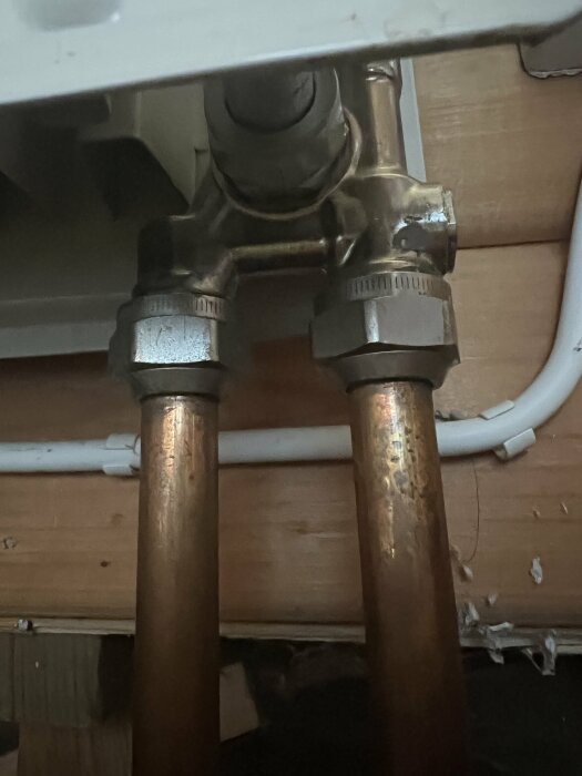 VVS-installation under diskbänk, kopparledningar och avstängningsventiler. Nedsläckt och lite suddig bild.