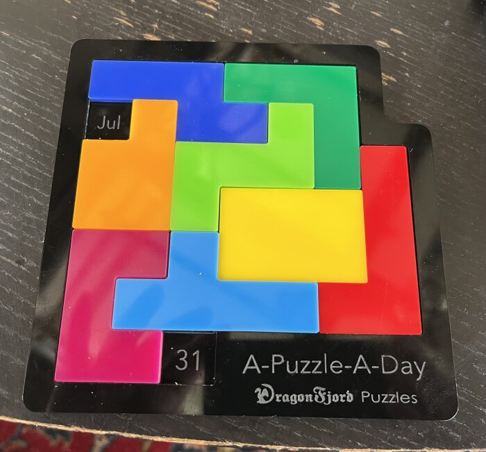 Färgglad, geometrisk pusselbitar, "A-Puzzle-A-Day", "Dragon Fjord Puzzles", svart bakgrund, logiskt tänkande, kort datum "Jul 31".