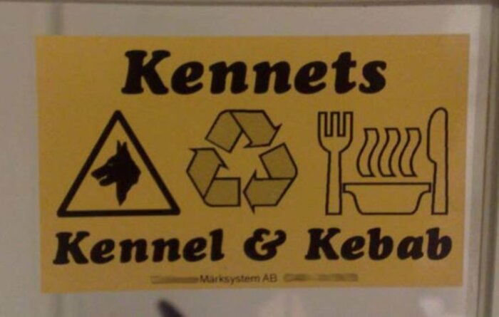 Gul skylt med svart text "Kennets Kennel & Kebab", ikoner för hund, återvinning och mat.