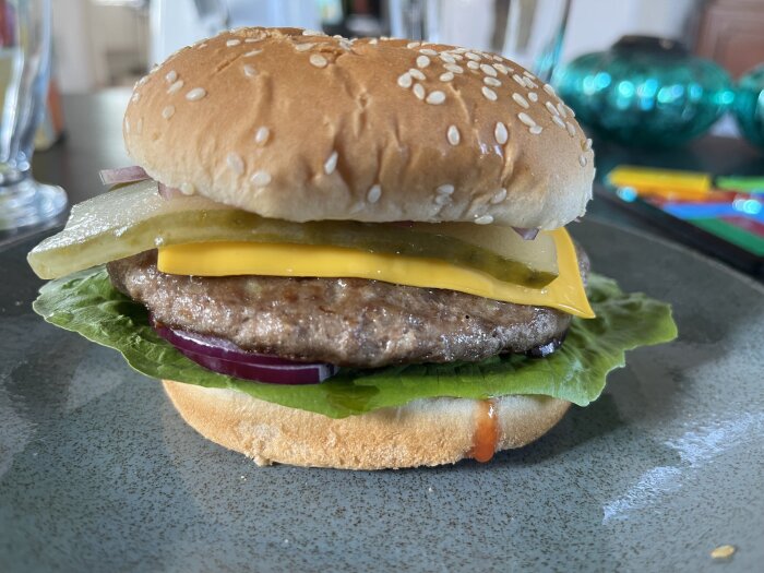 En hamburgare med ost, sallad, gurka, lök, köttbulle på en tallrik.