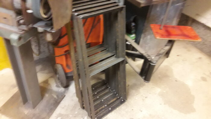 Oskarp bild av industriell miljö med stålhyllor och orangea säkerhetsvästar i bakgrunden.