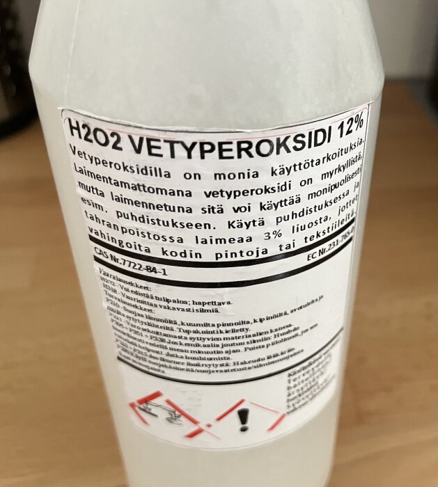 Flaska med etikett: H2O2 VETYPEROKSIDI 12%, varningsmärken, anvädningsinstruktioner, säkerhetsinformation på finska.