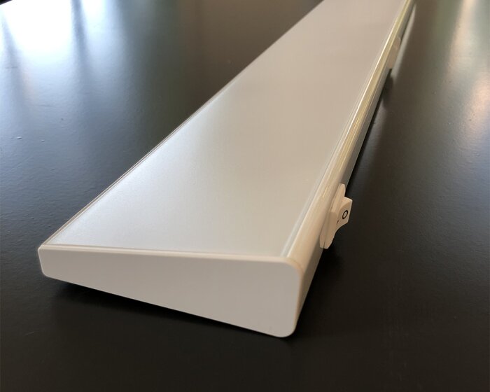 En vit långsträckt enhet med en slät yta på ett blankt mörkt bord.
