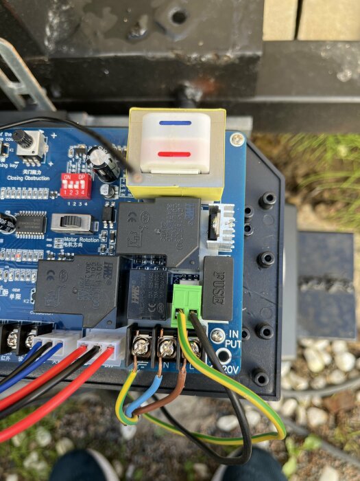 Elektronikskiva med kretsar, reläer, switchar och anslutna kablar, sannolikt styrenhet för mekanisk utrustning.