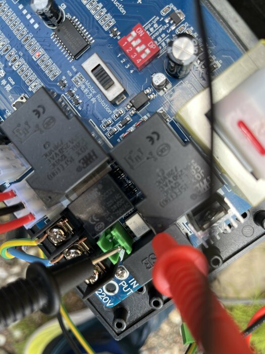 Elektronik-komponenter, SSD-reläer, kretskort, kablar, testprober, selektorer, text "220V". Närkontaktbild av elektrisk utrustning.