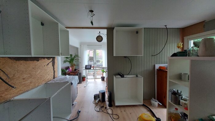 Renovering pågår; kök utan skåpluckor, verktyg, oskyddad elinstallation, öppen planlösning, dagsljus, hemlik miljö.