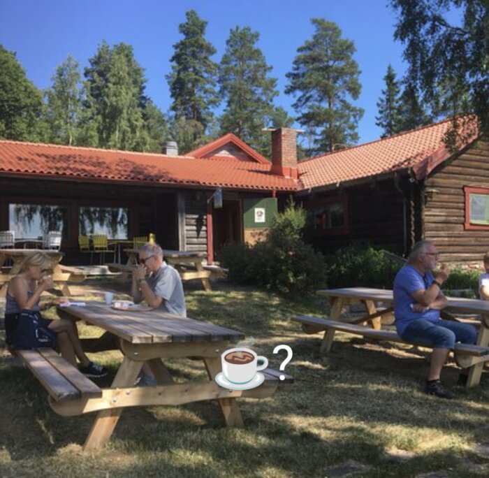 Trästuga, picknickbord, människor som äter, träd, klar himmel, grön gräs, avkopplande sommardag, café utomhus, kaffekopp emoji.