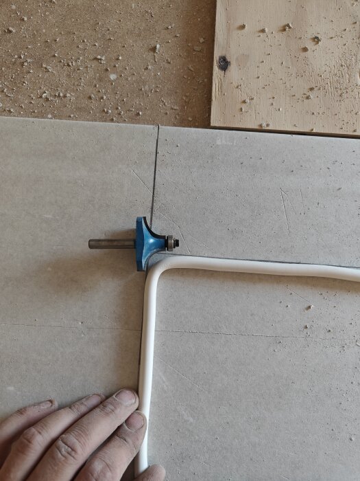 En person använder ett kakeljusteringsverktyg för att linjera plattor vid installation.