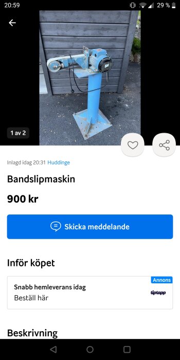 Blå bandslipmaskin till salu, placerad mot trävägg, annonserad online för 900 kr.