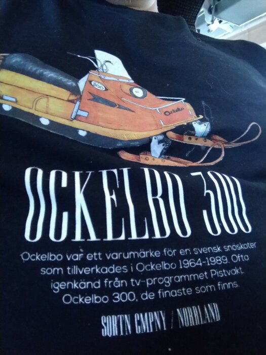 Tecknad skoter "Öckelbo 300" med figurer, text om svenskt varumärke och TV-programreferens, på t-shirt.