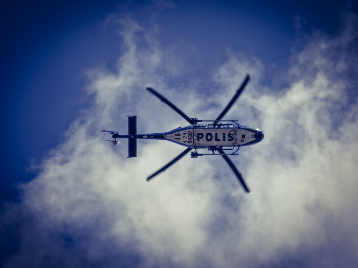 Polishelikopter flyger mot molnig himmel. Säkerhet, övervakning, transport, teknik, tjänsten, luftfart.