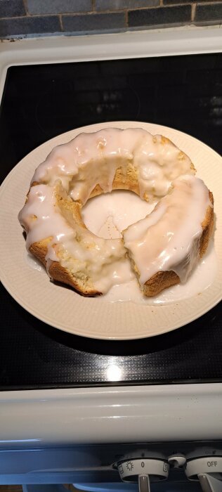 Ett sockerglaserat kaffebröd i ringform på en tallrik ovanpå en spis.