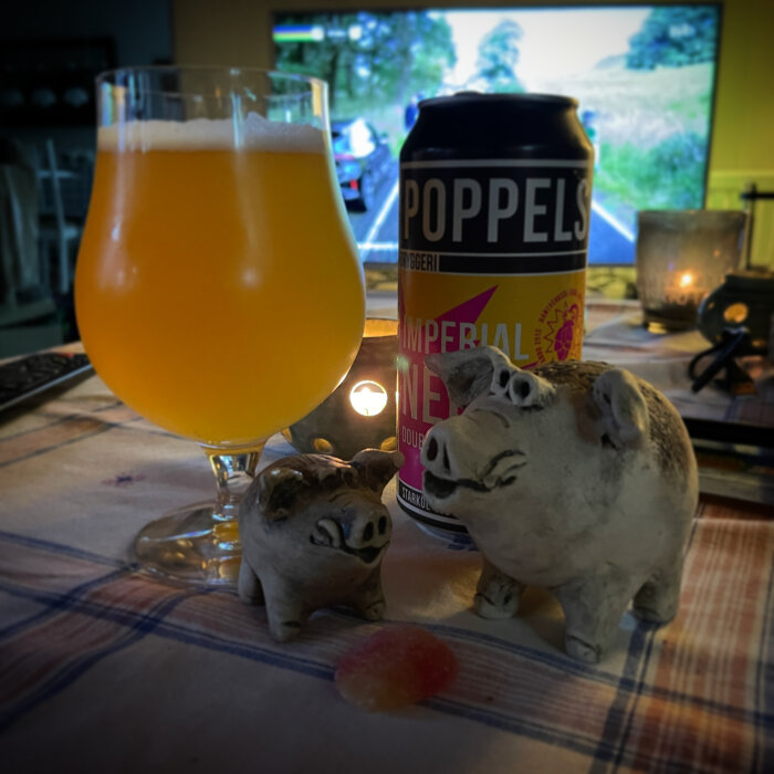 Ölglas, Poppels ölburk, två keramikgrisar, ljus och godis på lantligt bord.