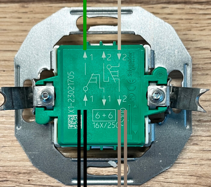 Elektrisk utrustningsdetalj med kretskortsanslutningar och metallfästen på träbakgrund.