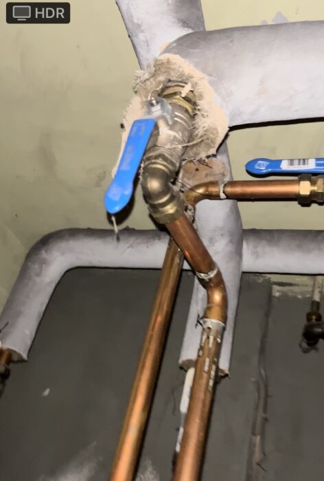 VVS-installation med kopparledningar och ventil, isolering behöver förbättras, taggar hänger på ventilen.