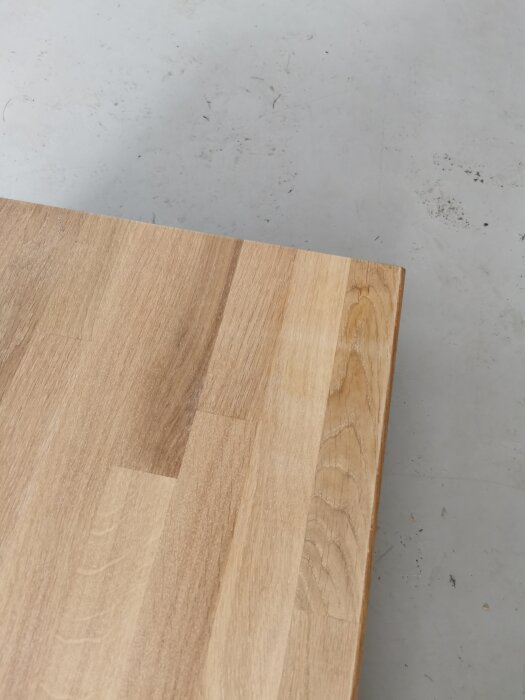 Träskärbräda på en grå yta, hörnet i fokus, naturligt trämaterial, enkelt och rent design.