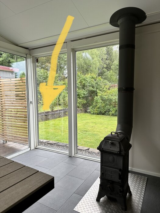 Utrymme med kamin, fönsterdörrar som leder till trädgården, grönska utanför, samtida stil, grått golv.