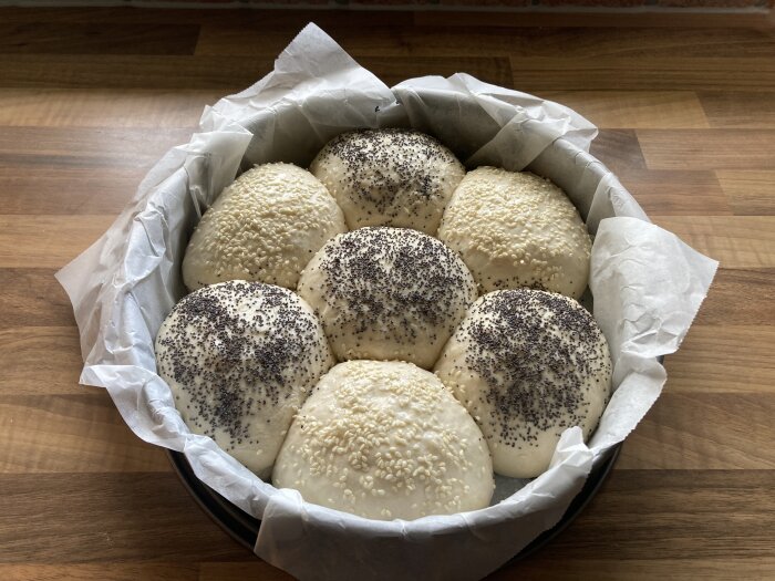 Degklumpar med sesam- och vallmofrön i bakform, redo att gräddas.