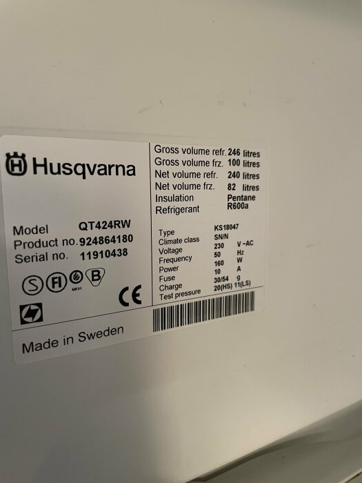 Etikett från Husqvarna-produkt visar model, serienummer, specifikationer som volym, isolering, köldmedium, elkrav. "Made in Sweden."