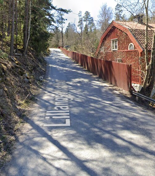 Asfaltsväg, rödmålat trähus, korrosionsfärgat staket, träd, skuggor, dagtid, blå himmel, fridfull, svensk landsbygd.