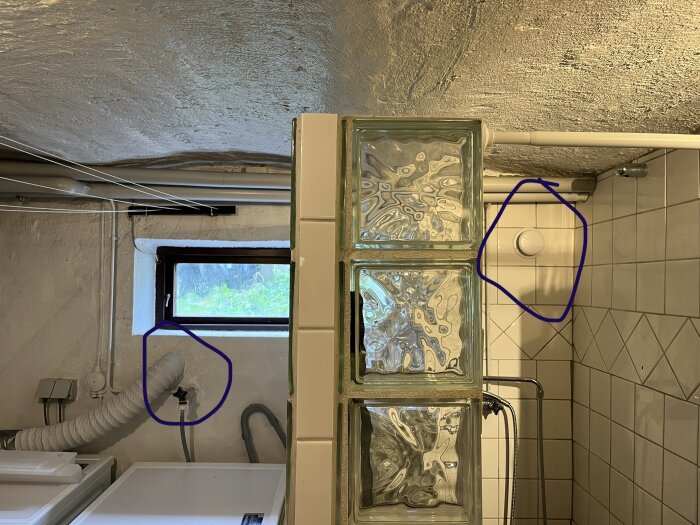 Ett tvättrum med frys, fönster, rör och glasblocksvägg. Markeringar kring ett strömuttag och ett fönster.