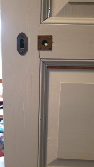 Dörrstängning med lås, dörrbleck, och synlig dörrkarm i närbild.