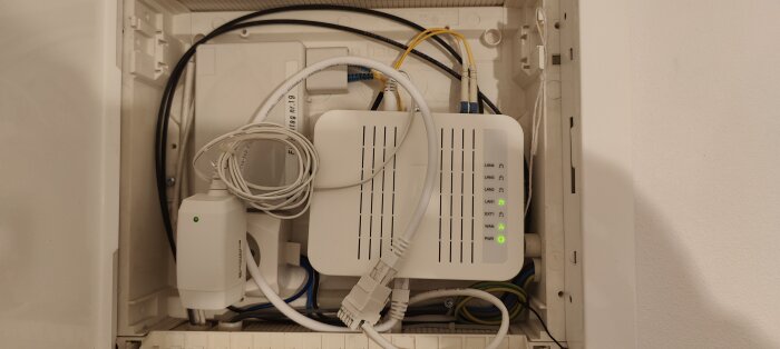 Nätverksskåp med router, switch, kablar och fiberkonverteringsutrustning. Organiserat men trångt. Teknisk infrastruktur för internetuppkoppling.