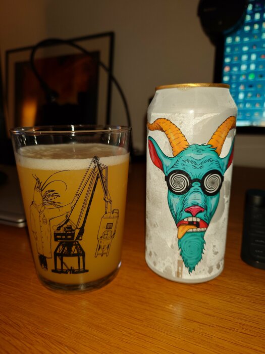 Ett ölglas med illustration och en ölburk med tecknad get på ett bord.