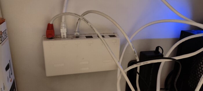 Nätverksuttag med flera anslutna Ethernet-kablar i oordning, kring teknisk utrustning och blå LED-belysning.