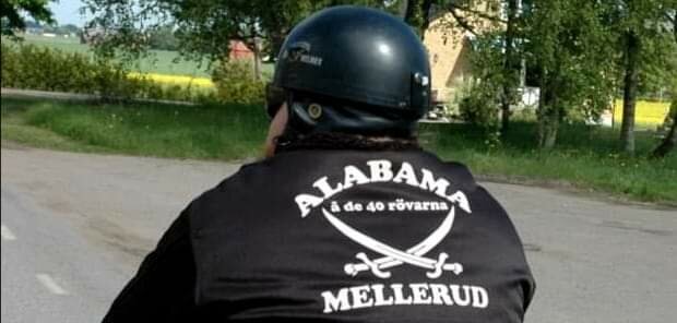 Person med hjälm och väst med texten "ALABAMA de 40 rövarna MELLERUD" på ryggen, utomhus, dagtid.