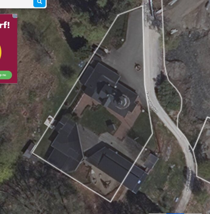 Satellitbild av ett stort hus med flera tak och en omgivande inhägnad.