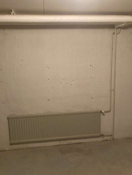 Vitrum med rör och radiator, oavslutad, spår efter borttagna föremål, möjlig renovering eller underhåll.