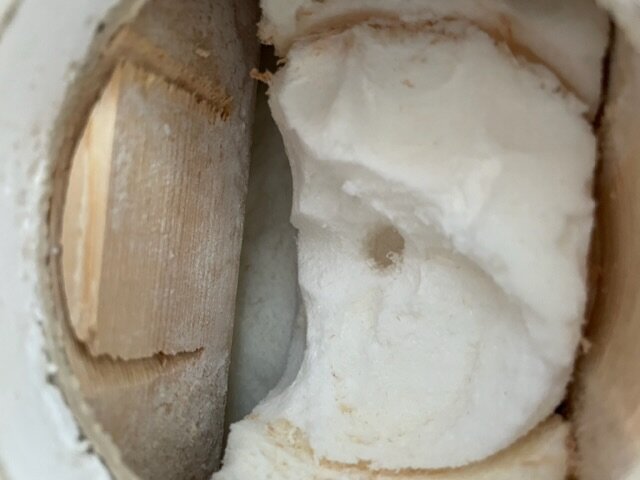 Närbild på öppnad kokosnöt med synligt fruktkött och brun skalrester.