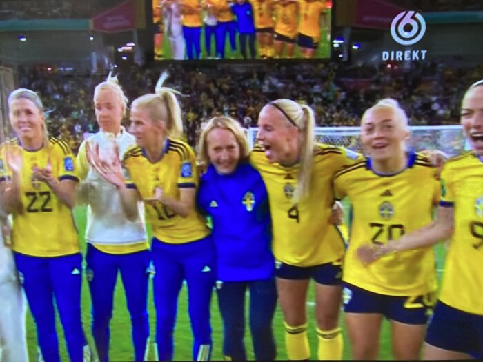 Ett fotbollslag i gula tröjor firar, troligen efter en vinst, med glädje och sammanhållning. (Blurry bildkvalitet)