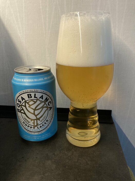 Ölburk och fyllt ölglas på bänk, blå etikett, skum, Rosa Blanca, bryggd för att förfriska Mallorca.