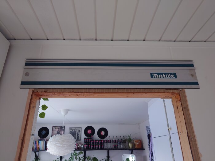 En Makita luftkonditioneringsenhet monterad ovanför en dörröppning inne i ett rum med dekorativa objekt.